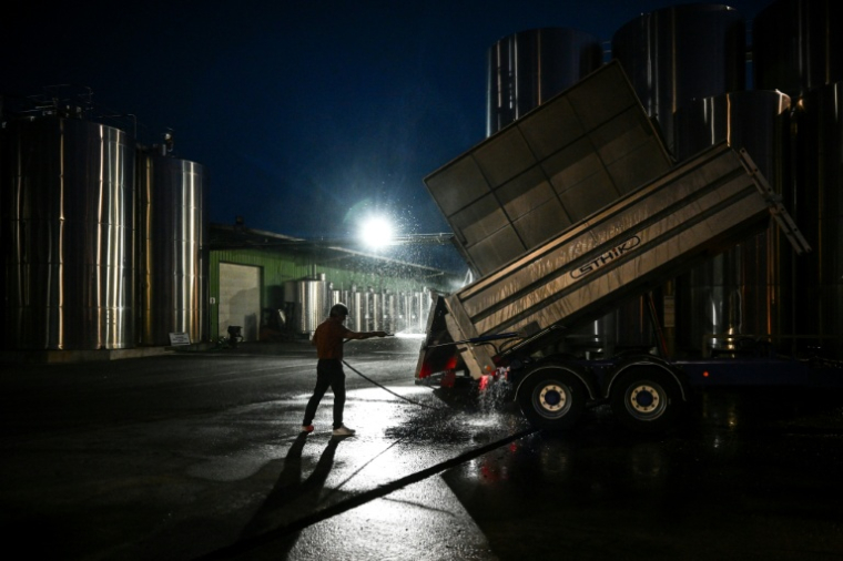 Avant que l'aube ne pointe, un employé nettoie une remorque durant la période des vendanges sur une propriété viticole à Val-de-Livenne, en Gironde, le 6 septembre 2023 ( AFP / Philippe LOPEZ )