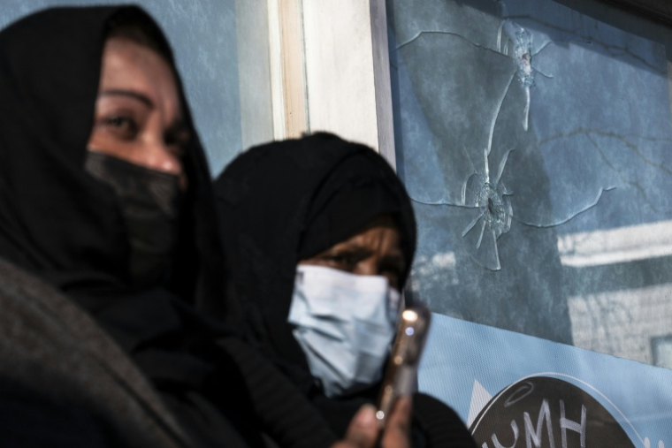 Deux femmes américano-somaliennes se tiennent, le 26 janvier 2026, devant une fenêtre brisée par des impacts de balle survenus, selon le propriétaire de l’établissement, lorsque Alex Pretti a été abattu par des agents fédéraux à Minneapolis ( AFP / ROBERTO SCHMIDT )