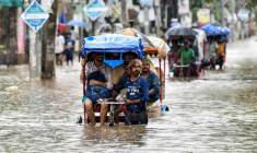 Des habitants se déplacent en cyclo-pousse dans une rue inondée après de fortes pluies à Guwahati, dans le nord-est de l'Inde, le 31 mai 2025 ( AFP / Biju BORO )