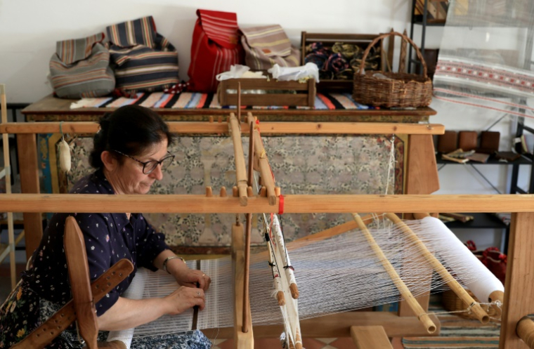 Mimoza Pjetraj travaille sur un métier à tisser avec des fils de soie dans son atelier du village de Dajc, dans la région de Zadrima, le 27 mai 2025 en Albanie ( AFP / Adnan Beci )