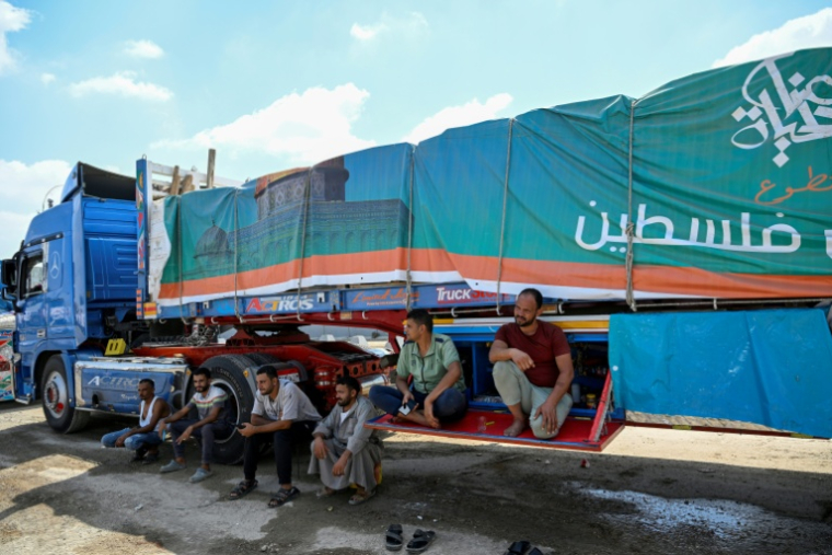 Des chauffeurs attendent à côté d'un camion chargé d'aide pour Gaza du côté égyptien au point de passage de Rafah, le 18 août 2025 ( AFP / Khaled DESOUKI )