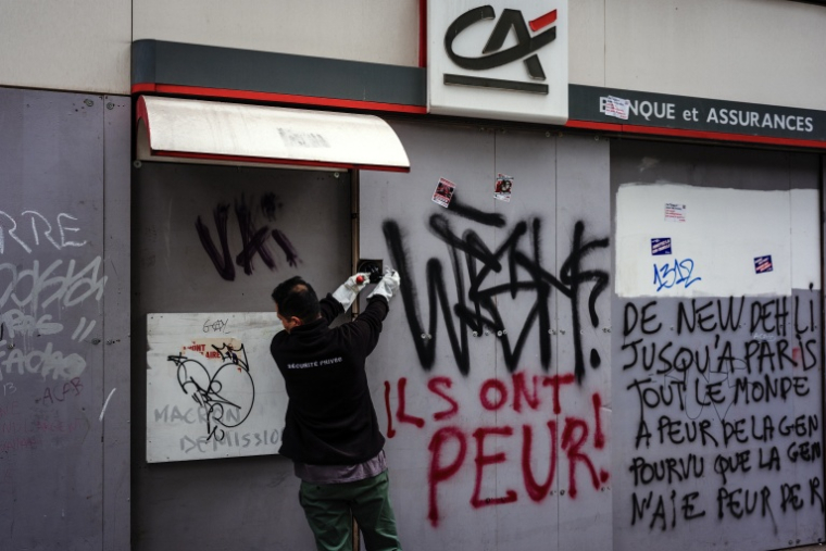 Un employé répare un distributeur de billets endommagé lors des manifestations du week-end à Paris, le 19 octobre 2026 ( AFP / DIMITAR DILKOFF )