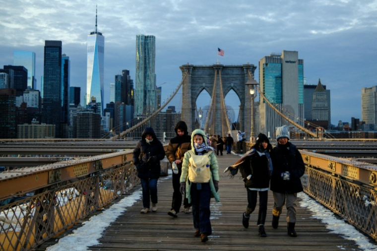 Des passants bravent le froid en traversant le pont de Brooklyn, dans le quartier de Manhattan à New York, le 21 janvier 2026 ( AFP / CHARLY TRIBALLEAU )