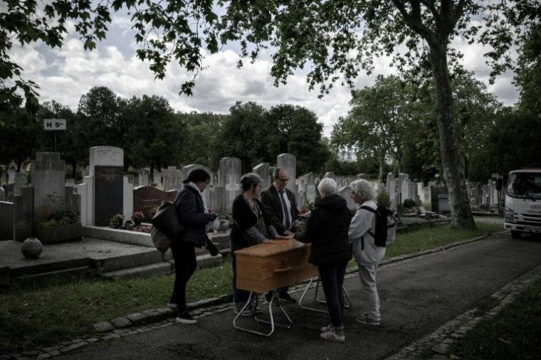 Des membres du collectif "Morts sans Toi(t)" se recueillent devant la tombe d'une personne décédée seule au cimetière de La Guillotière, le 11 mai 2026 à Lyon,dans le Rhône  ( AFP / Jeff PACHOUD )