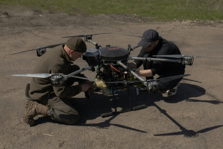 Des militaires ukrainiens de la 67e brigade mécanisée fixent des engins explosifs sur un drone bombardier lourd lors d'un exercice d'entraînement dans un lieu tenu secret de la région de Dnipropetrovsk, le 17 avril 2026 ( AFP / Roman PILIPEY )