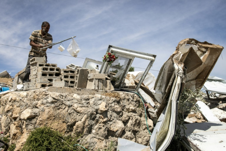 Un Palestinien récupère des objets dans les décombres d'une maison démolie dans le hameau de Khallet Al-Dabaa, en Cisjordanie occupée, le 6 mai 2025, après la destruction par les forces israéliennes des habitations de ce village ( AFP / JOHN WESSELS )