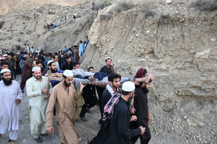 Des mineurs de charbon et des proches transportent le corps d’un mineur après l’effondrement d’une mine de charbon dans la région de Surange, à une cinquantaine de kilomètres à l’est de Quetta, le 30 juillet 2026 ( AFP / Banaras KHAN )