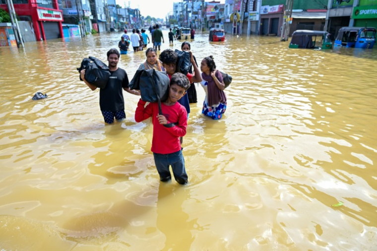 Des habitants emportent leurs biens dans une rue inondée de la banlieue de Colombo, la capitale du Sri Lanka, le 30 novembre 2025 ( AFP / Ishara S. KODIKARA )