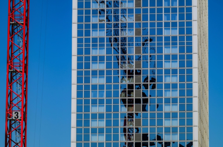 Une grue se reflète sur la façaade d'un immeuble à Berlin le 1er mai 2024 ( AFP / John MACDOUGALL )
