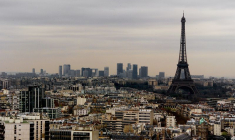 La tour Eiffel se dresse dans le ciel de Paris avec les bâtiments du centre d'affaires de La Défense en arrière-plan.