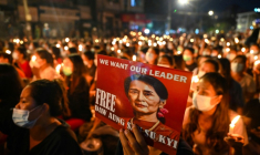 Un manifestant tient une affiche avec une image de l'ex-dirigeante détenue Aung San Suu Kyi lors d'une veillée aux chandelles à Rangoun, le 13 mars 2021 ( AFP / STR )