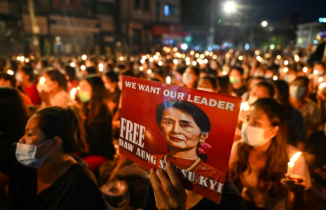 Un manifestant tient une affiche avec une image de l'ex-dirigeante détenue Aung San Suu Kyi lors d'une veillée aux chandelles à Rangoun, le 13 mars 2021 ( AFP / STR )