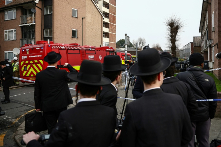 Des habitants sont rassemblés près d'un camion de pompiers après une attaque "antisémite" à Londres ayant visé quatre ambulances gérées par une association juive, le 23 mars 2026 ( AFP / Henry Nicholls )