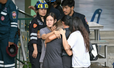 Des personnes réconfortent l’épouse d’un enseignant tué lors d’une fusillade dans une école de la province de Nonthaburi, au nord de Bangkok, le 7 août 2026 ( AFP / Lillian SUWANRUMPHA )