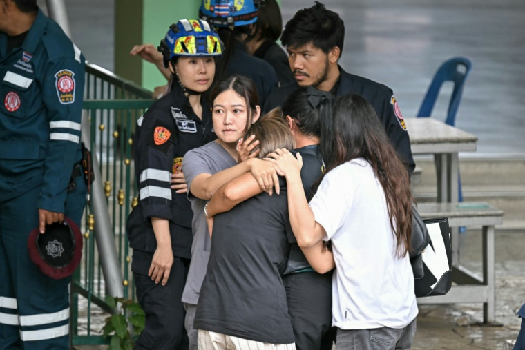 Des personnes réconfortent l’épouse d’un enseignant tué lors d’une fusillade dans une école de la province de Nonthaburi, au nord de Bangkok, le 7 août 2026 ( AFP / Lillian SUWANRUMPHA )