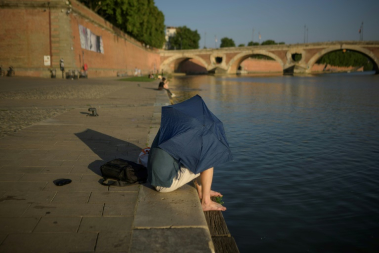Un homme se protège du soleil, le 20 juin 2025 à Toulouse ( AFP / Ed JONES )
