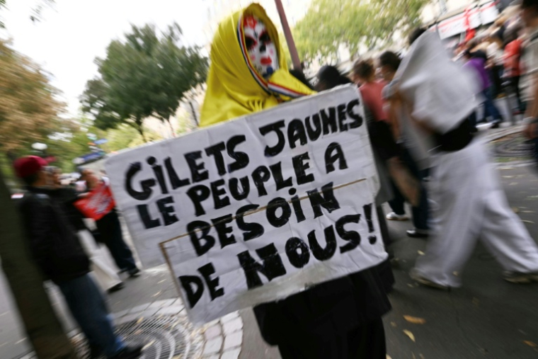 Un manifestant tient une pancarte en appelant aux gilets jaunes, le 13 octobre 2026 à Paris ( AFP / LOU BENOIST )