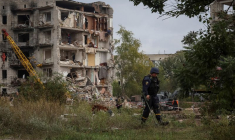 Les autorités travaillent autour et à l'intérieur d'un immeuble résidentiel endommagé par une frappe militaire russe à Izium, Ukraine