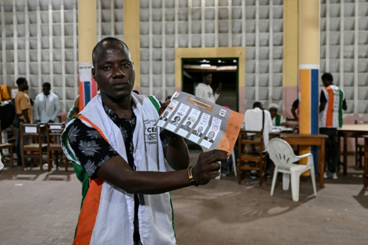 Un représentant de la commission électorale montre un bulletin de vote pour la présidentielle ivoirienne, à Abidjan le 25 octobre 2025 ( AFP / Sia KAMBOU )
