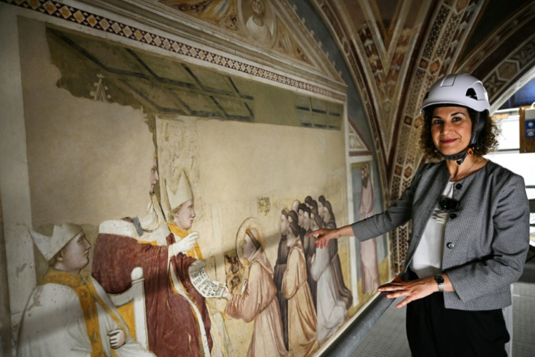 Renata Pintus, responsable du département de maçonnerie de l'Opificio delle Pietre Dure, présente une fresque lors d'une visite de presse marquant la fin des travaux de restauration des fresques du XIVe siècle de Giotto dans la basilique Santa Croce de Florence, le 12 juin 2026 en Italie ( AFP / Tiziana FABI )