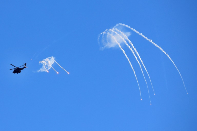 Une photo prise depuis une position à la frontière israélienne avec la bande de Gaza montre un hélicoptère Apache israélien lançant des fusées éclairantes au-dessus du territoire palestinien, le 29 août 2025 ( AFP / Jack GUEZ )