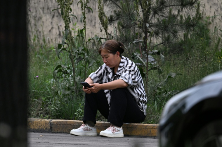 Une proche d'un des mineurs portés disparus après le coup de grisou dans le puits de Liushenyu, attend des nouvelles près de la mine de charbon, le 24 mai 2026 ( AFP / GREG BAKER )