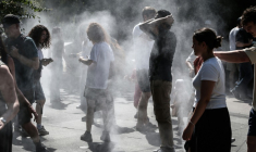 Des personnes se rafraîchissent au milieu de brumisateurs à Paris, le 1er juillet 2025, en période de canicule ( AFP / Thibaud MORITZ )
