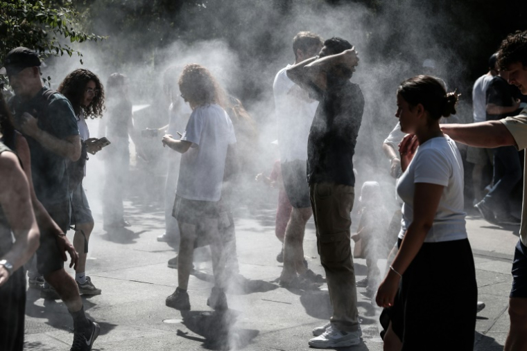 Des personnes se rafraîchissent au milieu de brumisateurs à Paris, le 1er juillet 2025, en période de canicule ( AFP / Thibaud MORITZ )