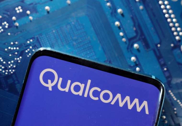 Un smartphone avec un logo Qualcomm affiché posé sur une carte mère d'ordinateur