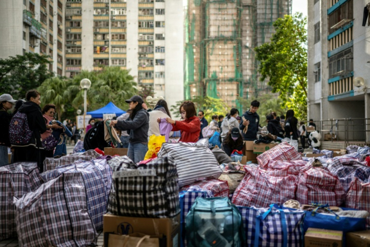 Distribution de produits de première nécessité aux sinistrés après l'incendie d'un groupe d'immeubles à Hong Kong, le 28 novembre 2025 ( AFP / Philip FONG )