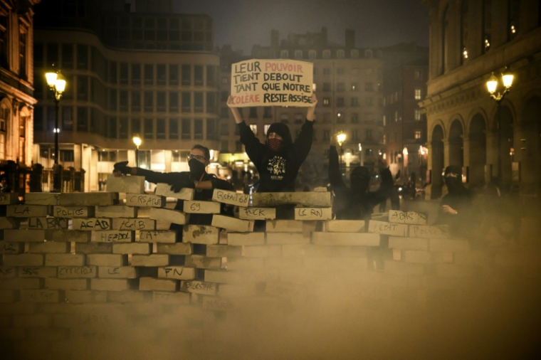 Des protestataires derrière une barricade érigée avec des pavés lors d'une manifestation contre la vie chère à Lyon, le 17 octobre 2026 ( AFP / JEFF PACHOUD )