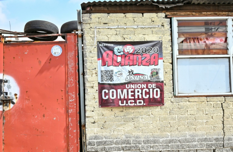 Une affiche sur le mur d'une entreprise indique un signe d'affiliation payante à des groupes qui garantissent la sécurité contre l'extorsion à Ecatepec, dans l'État de Mexico, le 2 octobre 2025 ( AFP / Yuri CORTEZ )