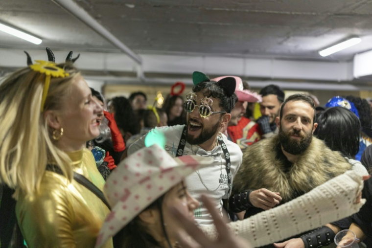 Des Israéliens costumés rassemblés dans un parking servant d'abri lors des célébrations de Pourim, à Tel-Aviv, le 2 mars 2026 ( AFP / Ilia YEFIMOVICH )