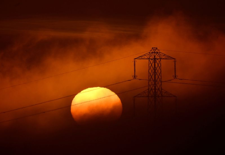 Le soleil se couche derrière un pylône électrique près de Petersfield, en Grande-Bretagne