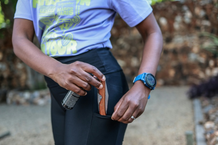 Nancy Masha montre le couteau et la bombe lacrymogène qu'elle emmène avec elle pour courir, à Irene (Afrique du Sud), près de Pretoria, le 21 septembre 2026 ( AFP / PHILL MAGAKOE )