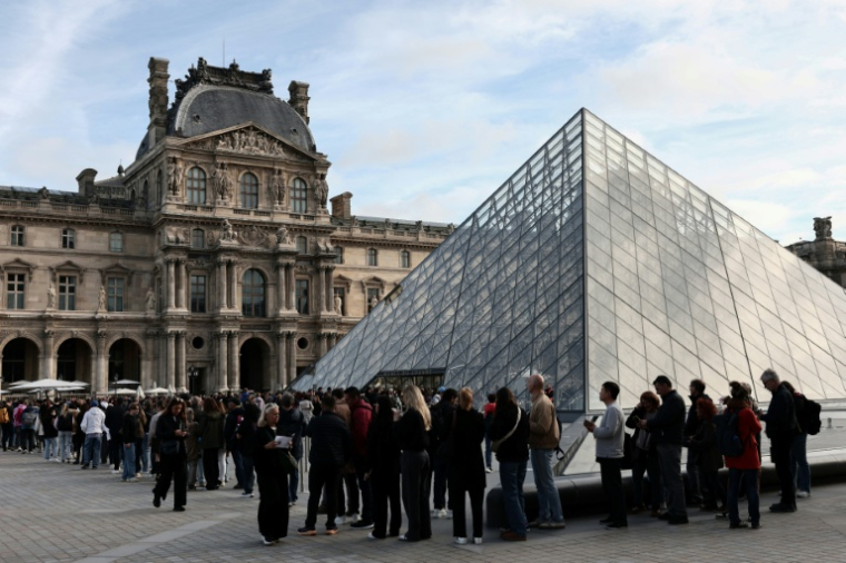Des visiteurs font la queue devant la Pyramide du Louvre, conçue par l'architecte sino-américain Ieoh Ming Pei, et le musée du Louvre le jour de sa réouverture après un vol de bijoux, le 22 octobre 2025 à Paris ( AFP / Thibaud MORITZ )