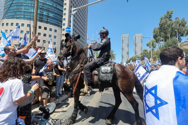 Des manifestants font un geste en direction d'un policier israélien lors de la "Journée de perturbation" à Tel Aviv, Israël