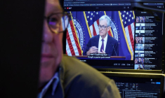 Un trader travaille, alors qu'un écran diffuse une conférence de presse du président de la Réserve fédérale américaine Jerome Powel