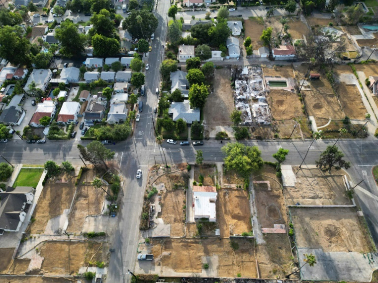 Vue aérienne de terrains résidentiels dégagés après la destruction de maisons lors de l'incendie d'Eaton en janvier 2025, à côté de maisons encore debout, le 20 août 2025 à Altadena, en Californie ( AFP / Robyn Beck )