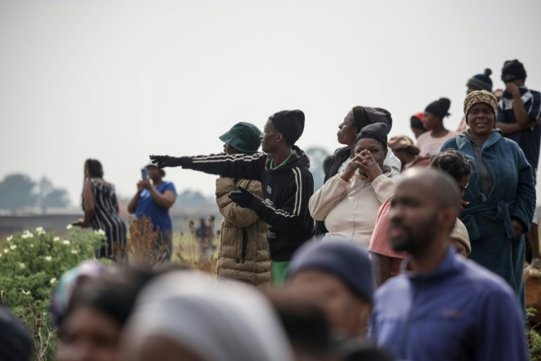 Des gens se rassemblent et pointent du doigt le lieu où le corps d'une femme a été découvert à Boksburg, à l'est de Johannesburg, le 17 septembre 2026 ( AFP / EMMANUEL CROSET )