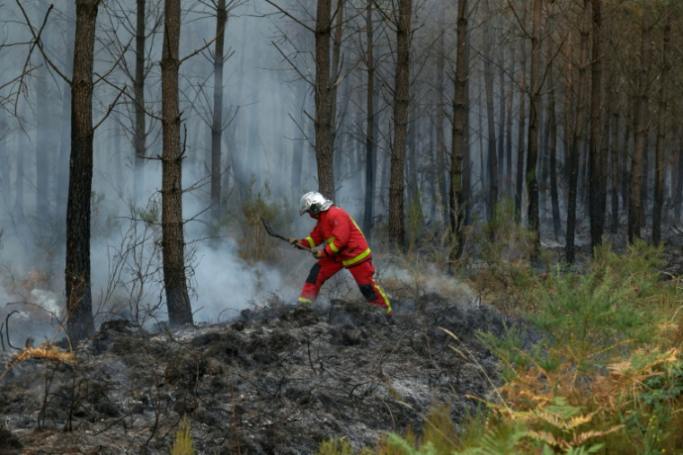 Un pompier éteint avec une pelle les débris d'un incendie qui couvent à Marcheprime, à l'ouest de Bordeaux, le 26 juillet 2026  ( AFP / Alain JOCARD )