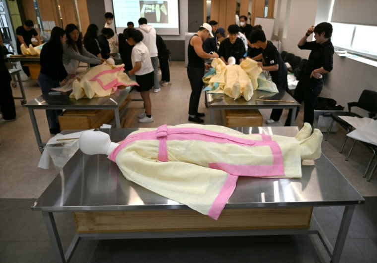 Des étudiants s'entraînent sur un mannequin au rite de la mise en bière dans une salle de classe de l'Institut des sciences et technologies de Busan, dans le sud-est de la Corée du Sud, le 24 septembre 2025 ( AFP / Jung Yeon-je )