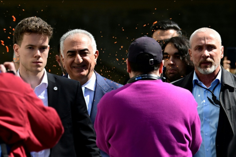 un activiste asperge de liquide rouge Reza Pahlavi, le fils du shah déchu d’Iran, à Berlin le 23 avril 2026.  ( AFP / John MACDOUGALL )