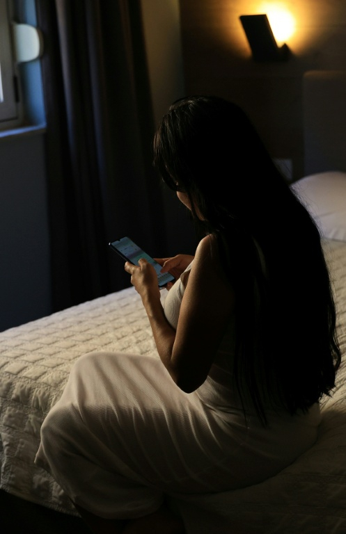 Maria (prénom d'emprunt), victime de trafic sexuel en provenance d'Amérique latine, consulte son téléphone lors d'une interview avec l'AFP à Tirana le 1er août 2025 en Albanie ( AFP / Adnan Beci )