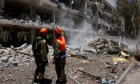 Des secouristes israléiens devant un immeuble lourdement endommagé par des frappes iraniennes à Tel-Aviv, le 22 juin 2025 ( AFP / Menahem Kahana )