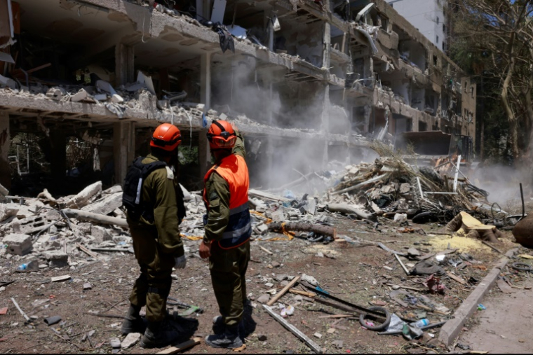 Des secouristes israléiens devant un immeuble lourdement endommagé par des frappes iraniennes à Tel-Aviv, le 22 juin 2025 ( AFP / Menahem Kahana )