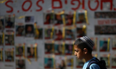 Des personnes passent devant des affiches montrant des photos d'otages enlevés lors de l'attaque du 7 octobre par le Hamas, à Tel Aviv