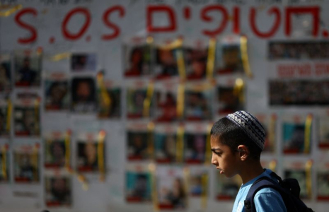Des personnes passent devant des affiches montrant des photos d'otages enlevés lors de l'attaque du 7 octobre par le Hamas, à Tel Aviv