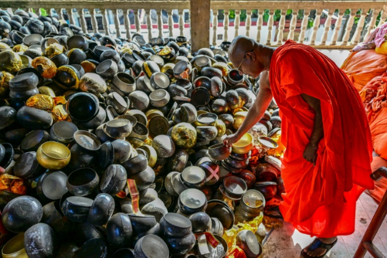 Kirinde Assagi, un moine bouddhiste montre des bols à aumônes, de mauvaise qualité, donnés au temple de Gangaramaya, à Colombo, le 7 juin 2025 ( AFP / Ishara S. KODIKARA )