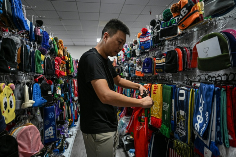 Shang Yabing, le directeur, trie des produits dans une salle d'exposition d'une usine qui produit des chapeaux et des écharpes à Yiwu, dans la province du Zhejiang, dans l'est de la Chine, le 18 septembre 2025 ( AFP / Jade GAO )